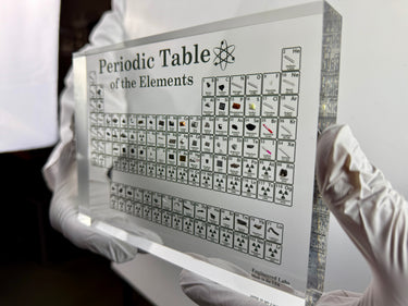 Periodic Table of Elements held by a person in white gloves