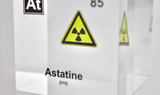 Clear acrylic cube displaying an Astatine element (Atomic Number 85) embedded within, offering a scientific presentation for collectors and science enthusiasts. Radiation symbol.