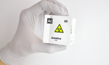 Clear acrylic cube displaying an Astatine element (Atomic Number 85) embedded within, offering a scientific presentation for collectors and science enthusiasts. Radiation symbol.