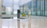Clear acrylic cube displaying a Berkelium element (Atomic Number 97) embedded within, offering a scientific presentation for collectors and science enthusiasts. Radiation symbol.