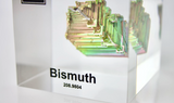 Clear acrylic cube displaying a Bismuth element (Atomic Number 83) embedded within, offering a scientific presentation for collectors and science enthusiasts.