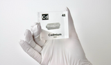 Clear acrylic cube displaying a Cadmium element (Atomic Number 48) embedded within, offering a scientific presentation for collectors and science enthusiasts.
