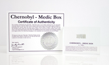 Clear acrylic display case featuring a historical fragment of a Chernobyl medic box, offering an educational presentation for collectors and those interested in nuclear history.