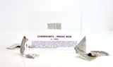 Clear acrylic display case featuring a historical fragment of a Chernobyl medic box, offering an educational presentation for collectors and those interested in nuclear history.