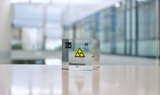 Clear acrylic cube displaying an Einsteinium element (Atomic Number 99) embedded within, offering a scientific presentation for collectors and science enthusiasts.