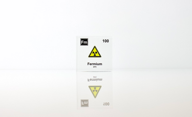 Clear acrylic cube displaying a Fermium element (Atomic Number 100) embedded within, offering a scientific presentation for collectors and science enthusiasts.