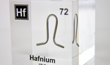 Clear acrylic cube displaying a Hafnium element (Atomic Number 72) embedded within, offering a scientific presentation for collectors and science enthusiasts.