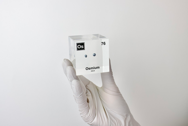 Piece of Osmium encased in a clear acrylic cube, with the element's name, atomic number, and properties displayed as on the periodic table for a sleek, educational display.