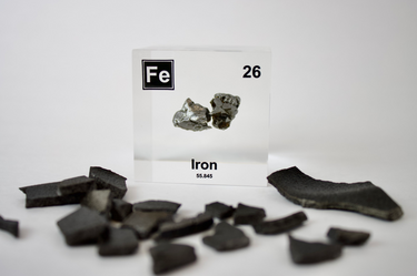 Iron element encased in a clear acrylic cube, featuring its name, atomic number, and key properties from the periodic table. A striking and educational display for science enthusiasts and collectors