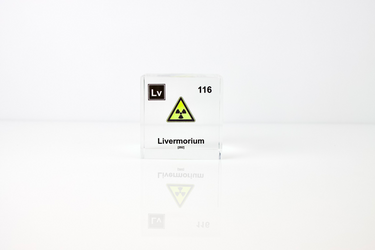 Clear acrylic cube displaying a Livermorium element (Atomic Number 116) embedded within, offering a scientific presentation for collectors and science enthusiasts.