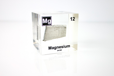 Clear acrylic cube featuring a Magnesium ampule with its atomic number 12. Ideal for educational displays, scientific collections, or as a distinctive decorative item.