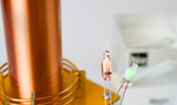 Clear acrylic cube encasing a Neon ampule with its atomic number 10. Ideal for display in educational settings, scientific collections, or as a decorative piece. Neon lights, lit up by a Tesla Coil nearby