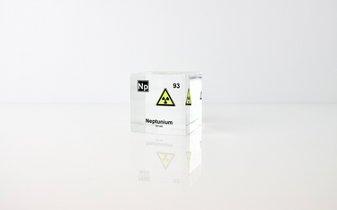 Clear acrylic cube displaying a Neptunium element (Atomic Number 93) embedded within, offering a scientific presentation for collectors and science enthusiasts.