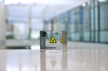 Clear acrylic cube displaying an Oganesson element (Atomic Number 118) embedded within, offering a scientific presentation for collectors and science enthusiasts.