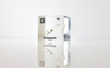 Clear acrylic cube displaying a Potassium element (Atomic Number 19) embedded within, offering a scientific presentation for collectors and science enthusiasts.