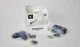 Clear acrylic cube displaying a Potassium element (Atomic Number 19) embedded within, offering a scientific presentation for collectors and science enthusiasts.