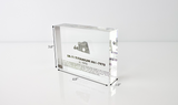 Close-up piece of SR-71 Blackbird titanium embedded in clear acrylic. The fragment is metallic and jagged, which highlights its history from the high-speed reconnaissance aircraft.