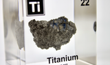 Clear acrylic cube displaying a Titanium element (Atomic Number 22) embedded within, offering a scientific presentation for collectors and science enthusiasts.