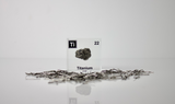 Clear acrylic cube displaying a Titanium element (Atomic Number 22) embedded within, offering a scientific presentation for collectors and science enthusiasts.