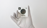 Clear acrylic cube displaying a Tungsten element (Atomic Number 74) embedded within, offering a scientific presentation for collectors and science enthusiasts.