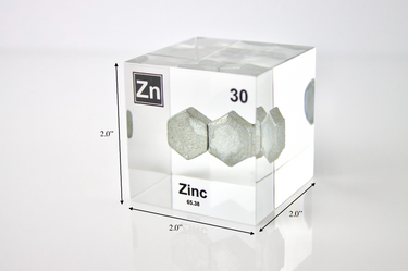 Zinc element encased in a clear acrylic cube, featuring its name, atomic number 30, and properties as displayed on the periodic table. Specifically showing its dimensions Ideal for educational and collector use.