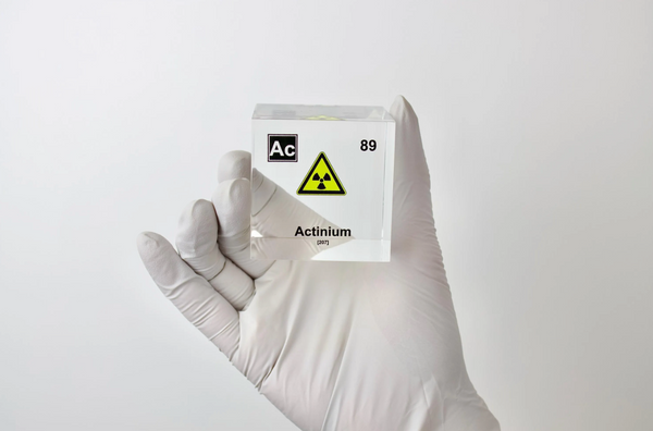 Clear acrylic cube displaying an Actinium element (Atomic Number 89) embedded within, offering a scientific presentation for collectors and science enthusiasts.