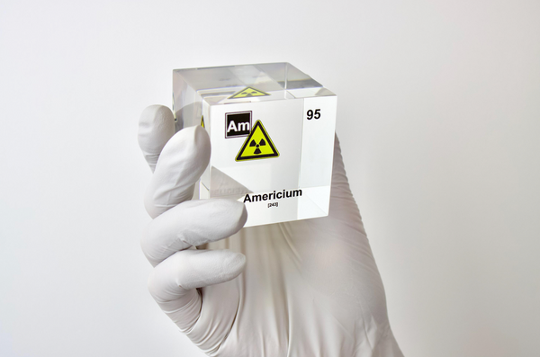 Clear acrylic cube displaying an Americium element (Atomic Number 95) embedded within, offering a scientific presentation for collectors and science enthusiasts. Radiation symbol.