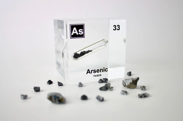 Arsenic element encased in a clear acrylic cube, showcasing its name, atomic number 33, and key properties from the periodic table. Surrounded by its raw material. An informative and visually striking piece ideal for educational purposes and collectors.