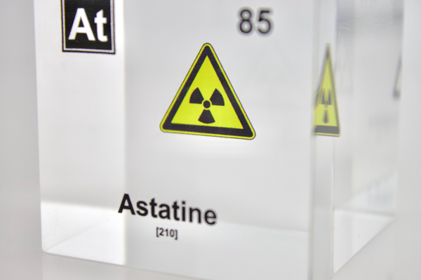 Clear acrylic cube displaying an Astatine element (Atomic Number 85) embedded within, offering a scientific presentation for collectors and science enthusiasts. Radiation symbol.