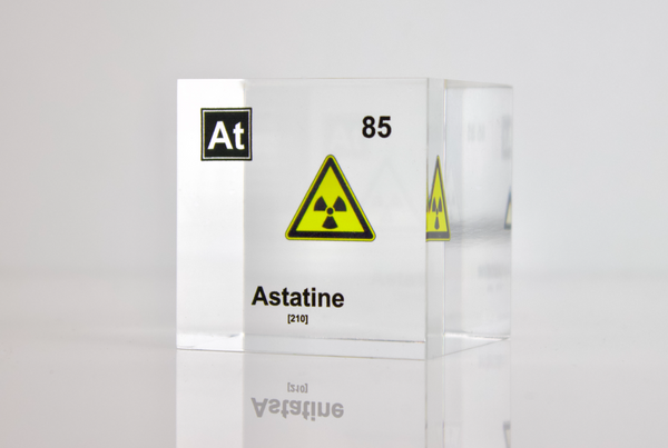 Clear acrylic cube displaying an Astatine element (Atomic Number 85) embedded within, offering a scientific presentation for collectors and science enthusiasts. Radiation symbol.