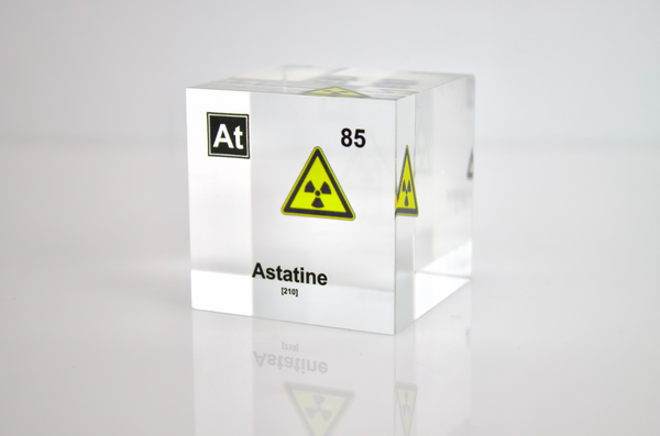 Clear acrylic cube displaying an Astatine element (Atomic Number 85) embedded within, offering a scientific presentation for collectors and science enthusiasts. Radiation symbol.