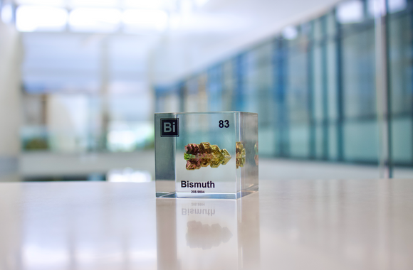 Clear acrylic cube displaying a Bismuth element (Atomic Number 83) embedded within, offering a scientific presentation for collectors and science enthusiasts.