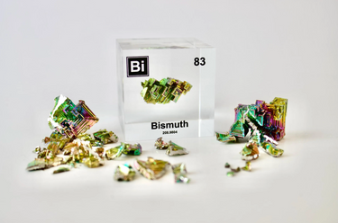 Clear acrylic cube displaying a Bismuth element (Atomic Number 83) embedded within, offering a scientific presentation for collectors and science enthusiasts.