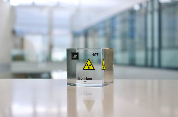 Clear acrylic cube displaying a Bohrium element (Atomic Number 107) embedded within, offering a scientific presentation for collectors and science enthusiasts. Radiation symbol.