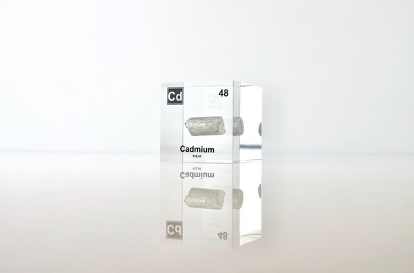 Clear acrylic cube displaying a Cadmium element (Atomic Number 48) embedded within, offering a scientific presentation for collectors and science enthusiasts.