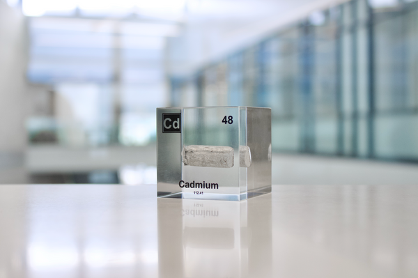 Clear acrylic cube displaying a Cadmium element (Atomic Number 48) embedded within, offering a scientific presentation for collectors and science enthusiasts.