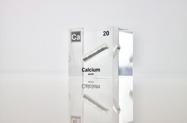 Clear acrylic cube displaying a Calcium element (Atomic Number 20) embedded within, offering a scientific presentation for collectors and science enthusiasts.