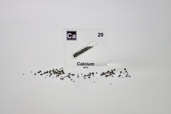 Clear acrylic cube displaying a Calcium element (Atomic Number 20) embedded within, offering a scientific presentation for collectors and science enthusiasts.