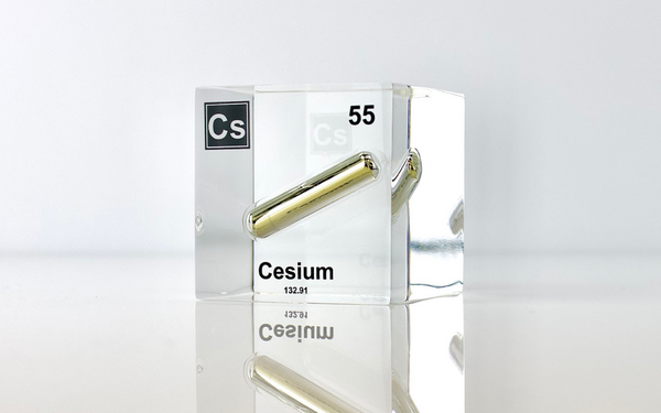 Clear acrylic cube displaying a Cesium element (Atomic Number 55) embedded within, offering a scientific presentation for collectors and science enthusiasts.