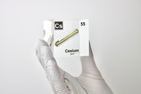 Clear acrylic cube displaying a Cesium element (Atomic Number 55) embedded within, offering a scientific presentation for collectors and science enthusiasts.