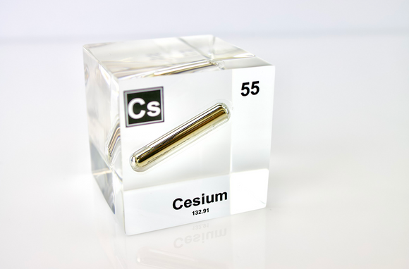 Clear acrylic cube displaying a Cesium element (Atomic Number 55) embedded within, offering a scientific presentation for collectors and science enthusiasts.