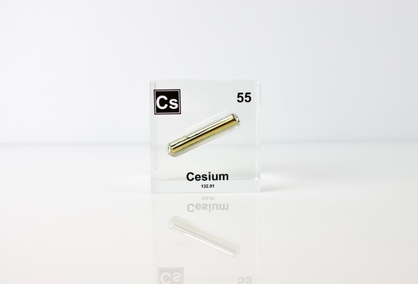 Clear acrylic cube displaying a Cesium element (Atomic Number 55) embedded within, offering a scientific presentation for collectors and science enthusiasts.