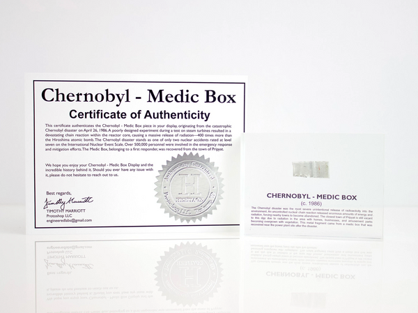 Clear acrylic display case featuring a historical fragment of a Chernobyl medic box, offering an educational presentation for collectors and those interested in nuclear history.