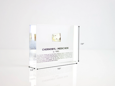 Clear acrylic display case featuring a historical fragment of a Chernobyl medic box, offering an educational presentation for collectors and those interested in nuclear history.