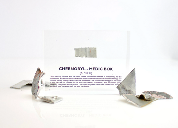 Clear acrylic display case featuring a historical fragment of a Chernobyl medic box, offering an educational presentation for collectors and those interested in nuclear history.