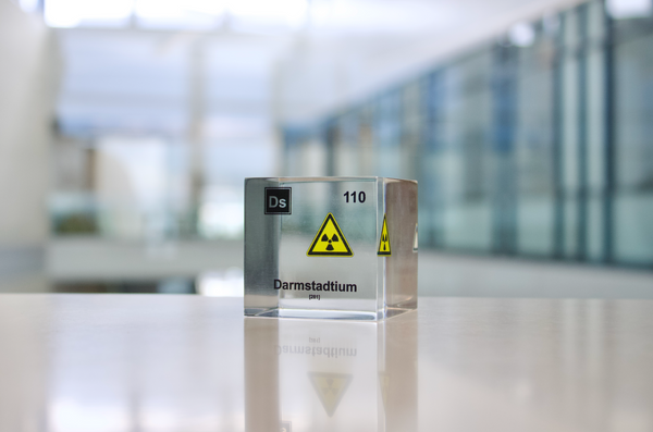 Clear acrylic cube displaying a Darmstadtium element (Atomic Number 110) embedded within, offering a scientific presentation for collectors and science enthusiasts.