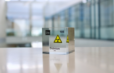 Clear acrylic cube displaying a Dubnium element (Atomic Number 105) embedded within, offering a scientific presentation for collectors and science enthusiasts.