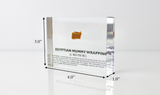Clear acrylic display case featuring fragments of Egyptian mummy wrappings, offering a historical and educational presentation for collectors and those interested in ancient history.