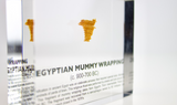 Clear acrylic display case featuring fragments of Egyptian mummy wrappings, offering a historical and educational presentation for collectors and those interested in ancient history.