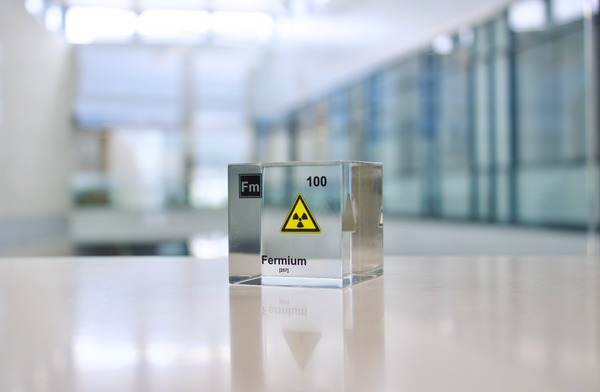 Clear acrylic cube displaying a Fermium element (Atomic Number 100) embedded within, offering a scientific presentation for collectors and science enthusiasts.